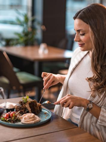 Vrouw in restaurant snijdt in stukjes biefstuk 