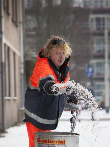 iemand strooit zout op de stoep vanwege sneeuw