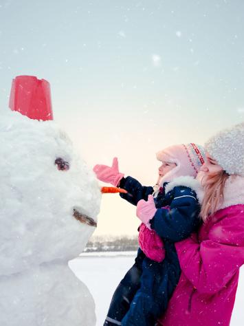 een moeder en kind maken een sneeuwpop af