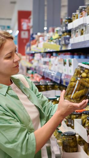 Vrouw in supermarkt kijkt naar pot augurken