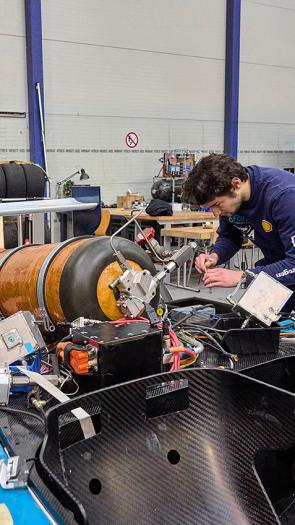 Twee jongens sleutelen aan een race auto met een waterstof tank