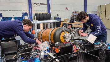 Twee jongens sleutelen aan een race auto met een waterstof tank