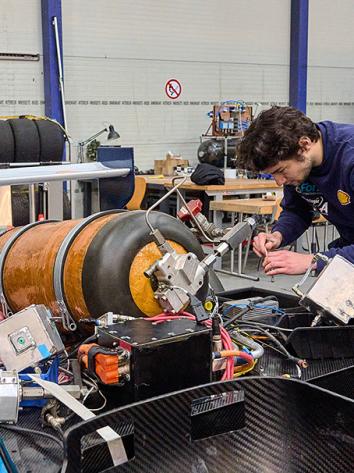 Twee jongens sleutelen aan een race auto met een waterstof tank