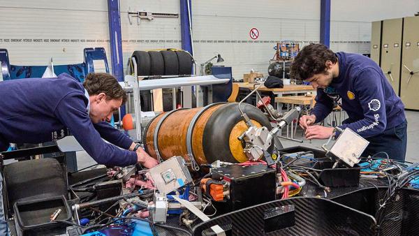 Twee jongens sleutelen aan een race auto met een waterstof tank