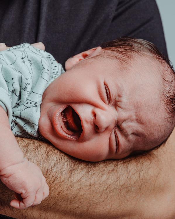 een ouder houdt de baby vast op diens arm