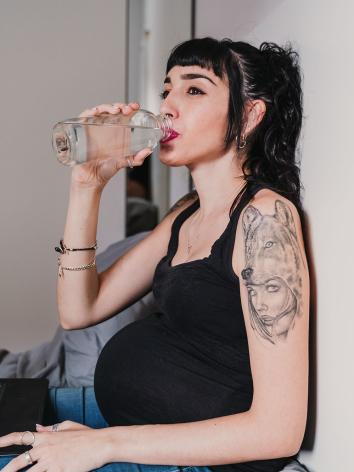 een zwangere vrouw drinkt uit een fles water