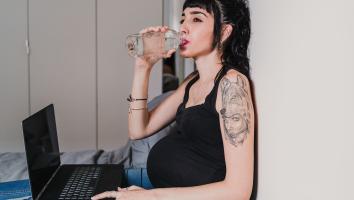 een zwangere vrouw drinkt uit een fles water