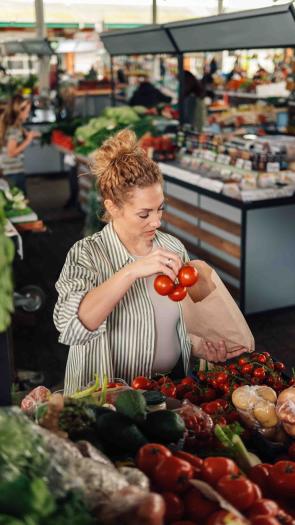 Vrouw koopt tomaten bij de supermarkt