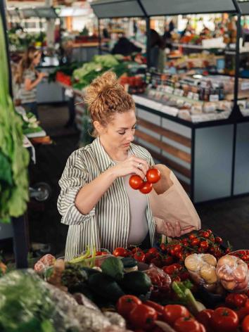 Vrouw koopt tomaten bij de supermarkt