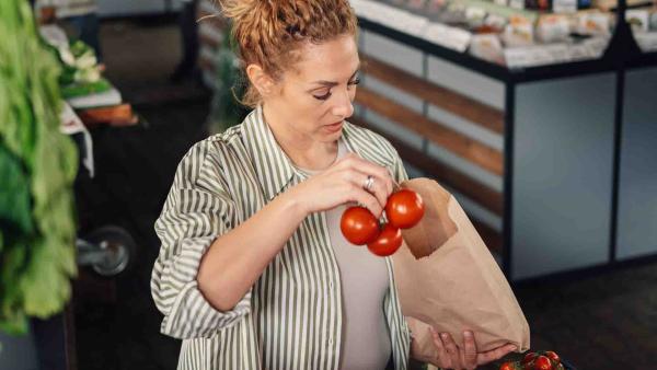 Vrouw koopt tomaten bij de supermarkt