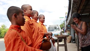 Een vrouw bidt voor boeddhistische monikken