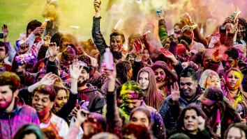 Mensen gooien gekleurd poeder naar elkaar tijdens de viering van Holi