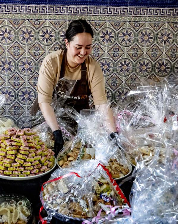 een medewerker van de bakker staat voor allerlei pakketten met Marokkaanse lekkernijen