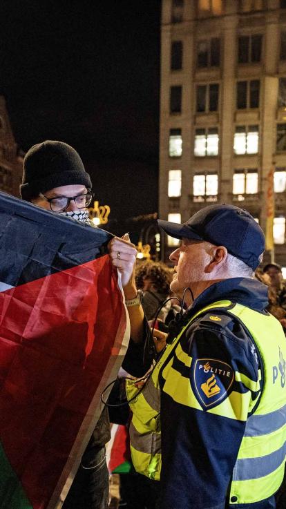 Politieagent gaat in gesprek met demonstrant.