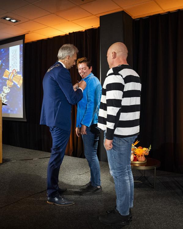 De burgemeester van Vianen spelt een lintje op bij een lachende vrouw