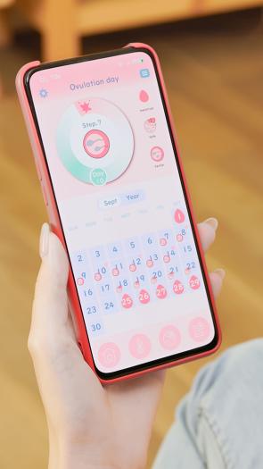 een vrouw kijkt op haar telefoon naar een app die de menstruatiecyclus bijhoudt