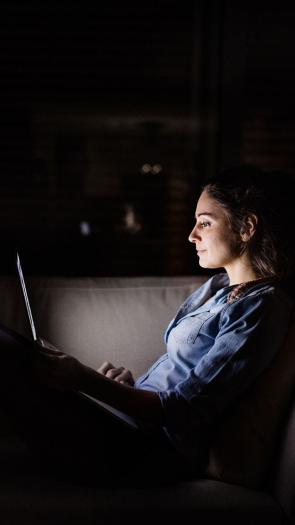 een vrouw kijkt in het donker op haar laptop