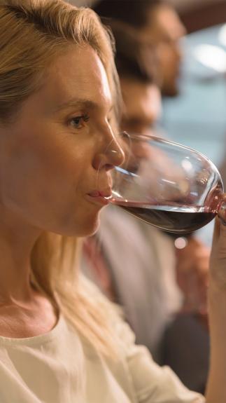 Vrouw drinkt uit glas rode wijn met serieuze blik