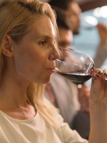 Vrouw drinkt uit glas rode wijn met serieuze blik
