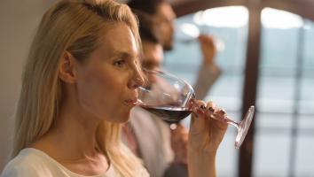 Vrouw drinkt uit glas rode wijn met serieuze blik