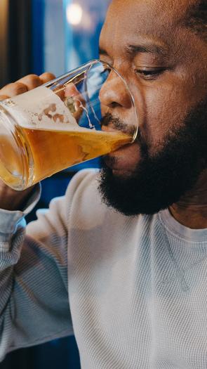 Een man drinkt uit een groot glas bier