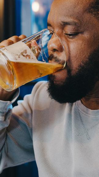 Een man drinkt uit een groot glas bier