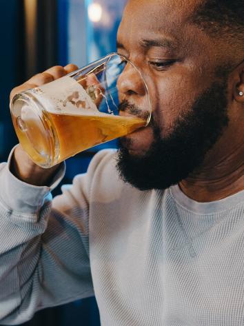 Een man drinkt uit een groot glas bier