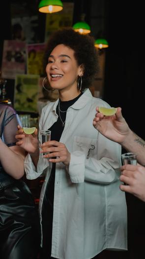 Een groep jonge mensen doet een shotje in een bar met een limoen in de hand