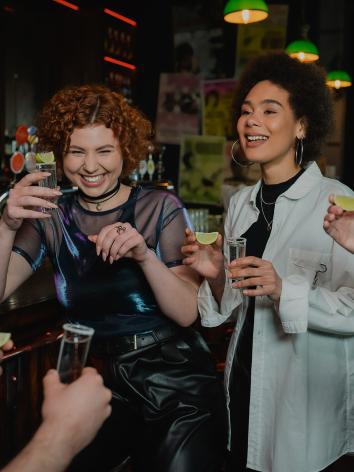 Een groep jonge mensen doet een shotje in een bar met een limoen in de hand