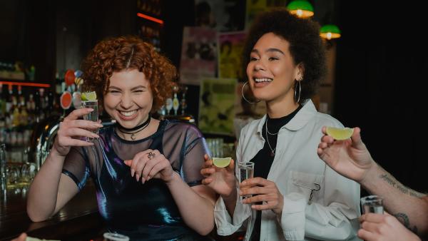 Een groep jonge mensen doet een shotje in een bar met een limoen in de hand