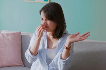 Vrouw knijpt neus dicht en trekt een vies gezicht