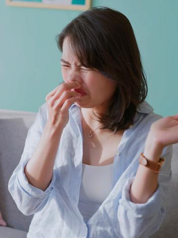 Vrouw knijpt neus dicht en trekt een vies gezicht