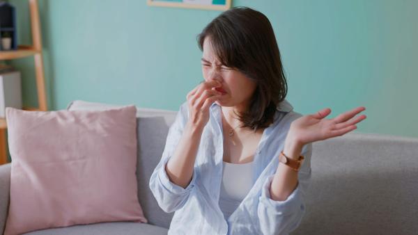 Vrouw knijpt neus dicht en trekt een vies gezicht