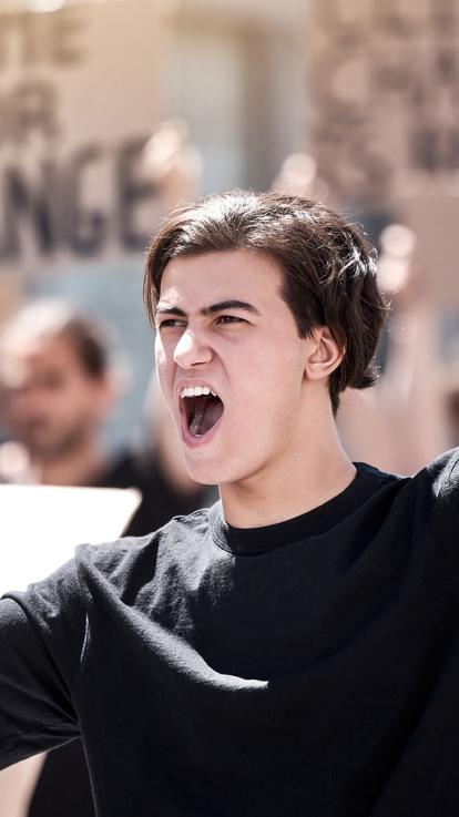 jongvolwassene roept met megafoon tijdens demonstratie.