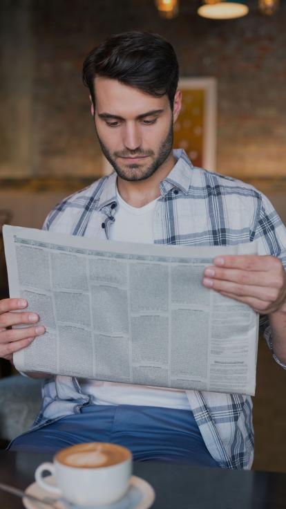 man leest aandachtig de krant in een café