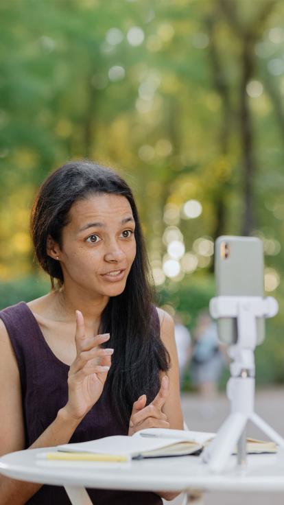 vrouw maakt een video-opname op haar smartphone terwijl ze spreekt in een park