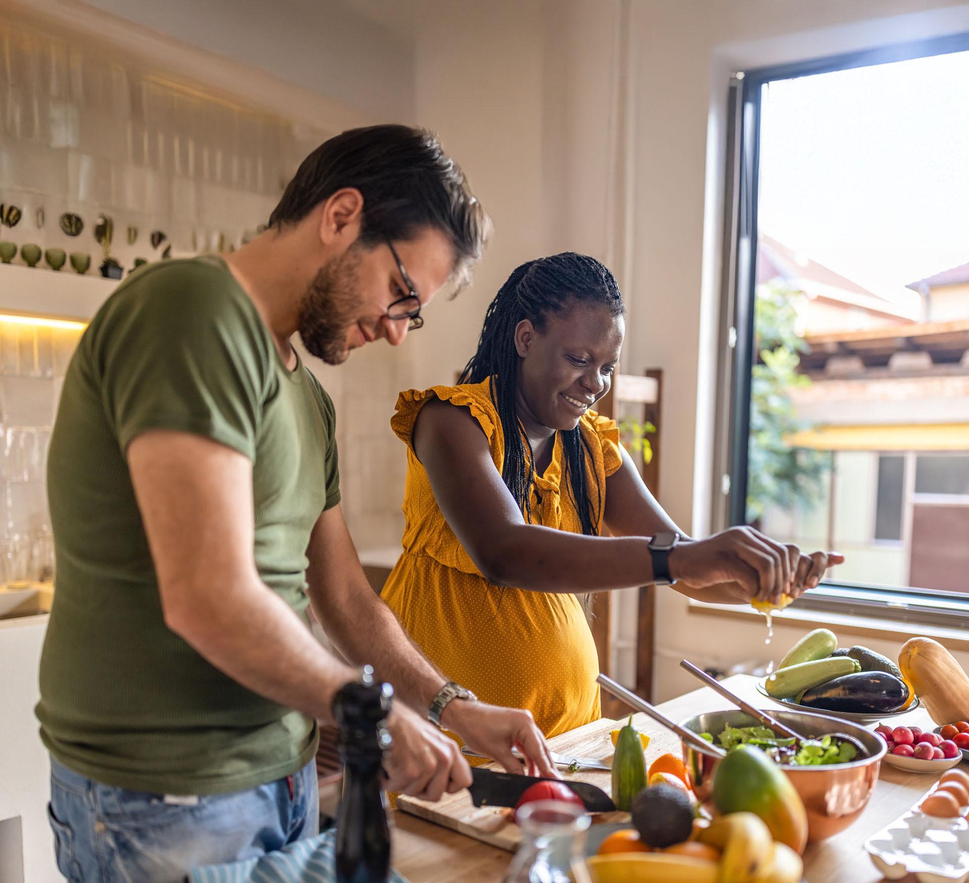 Een zwangere vrouw is bezig in de keuken om een gezonde maaltijd te koken.
