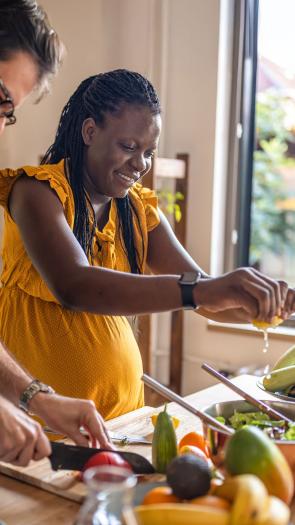 Een zwangere vrouw is bezig in de keuken om een gezonde maaltijd te koken.