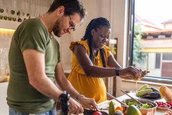 Een zwangere vrouw is bezig in de keuken om een gezonde maaltijd te koken.