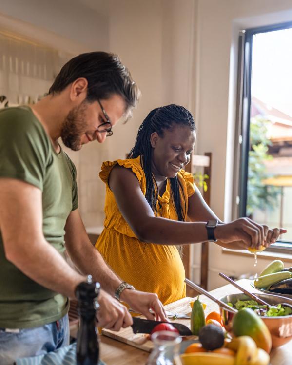 Een zwangere vrouw is bezig in de keuken om een gezonde maaltijd te koken.