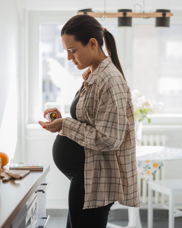 Een zwangere vrouw neemt wat supplementen bij om haar zwangerschap te bevorderen.