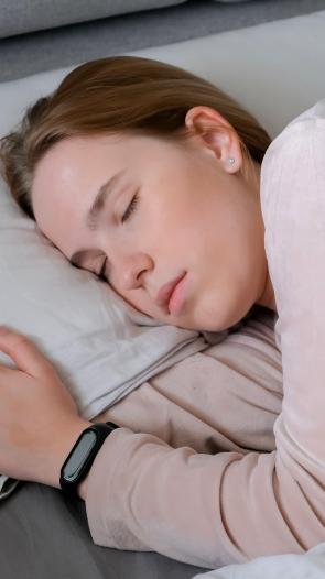 een vrouw slaapt in bed met een smartwatch aan haar pols