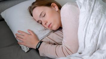 een vrouw slaapt in bed met een smartwatch aan haar pols