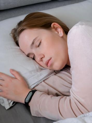 een vrouw slaapt in bed met een smartwatch aan haar pols