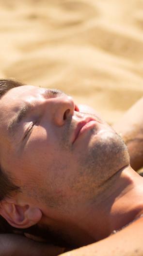 een man aan het zonnen op het strand