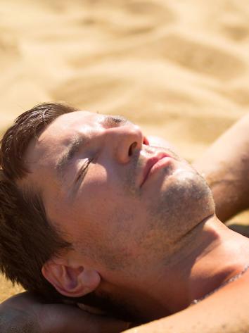 een man aan het zonnen op het strand