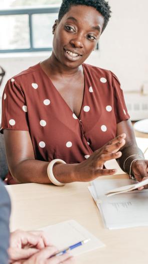 Een man van kleur en een witte vrouw hebben een gesprek op werk.