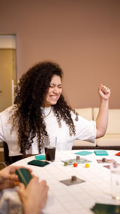 Vrouw juicht aan tafel bij het spelen van een bordspel