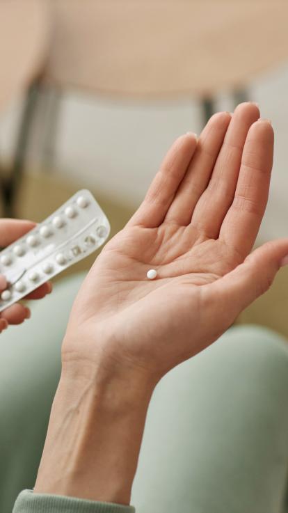 iemand houdt in de ene hand een pillenstrip en in de andere een pil