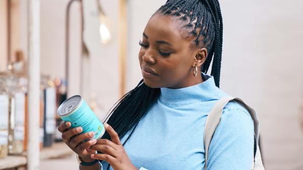 iemand kijkt bedenkelijk naar een blik groenten